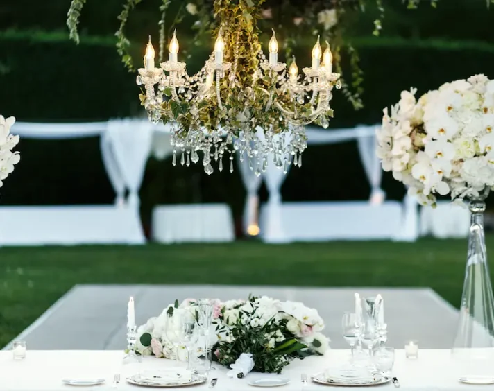 chandelier-with-flowers-greenery-hangs-dinner-table chair and table rentals for wedding